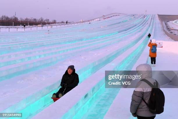 Tourists enjoy rides on an ice slide at the Harbin Ice and Snow World during the 40th Harbin International Ice and Snow Festival on January 5, 2024...