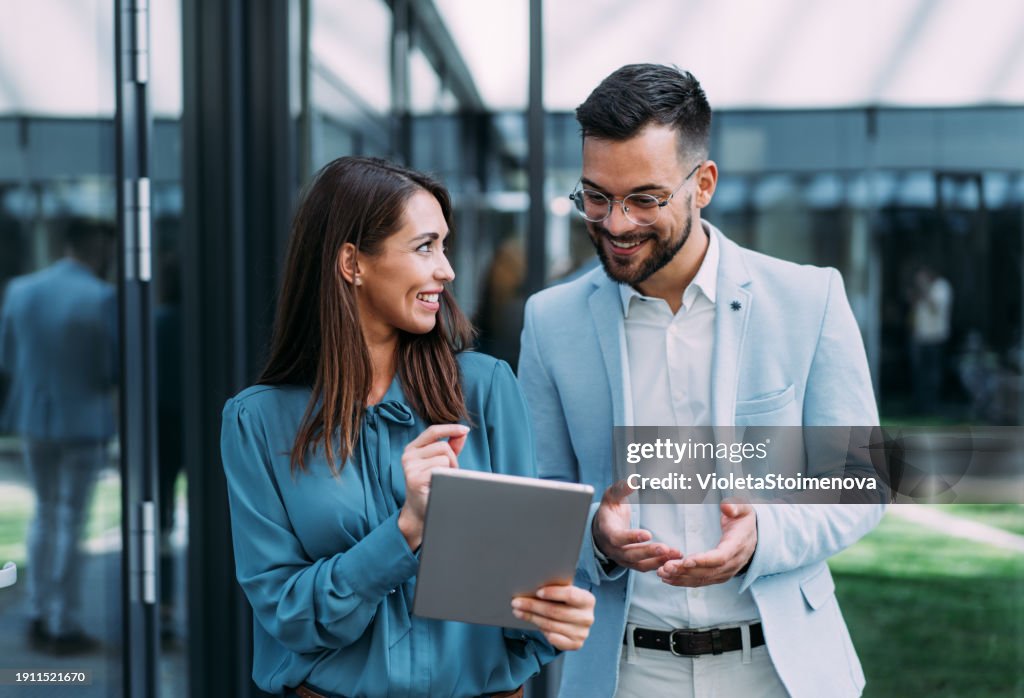 Business people using digital tablet outdoors.