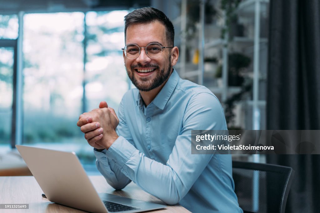 Successful businessman in modern office working on laptop.