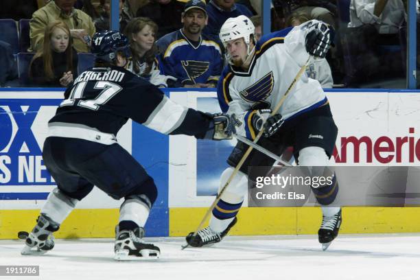 Reed Low of the St. Louis Blues advances the puck off the boards as he makes a move on Marc-Andre Bergeron of the Edmonton Oilers during the NHL game...