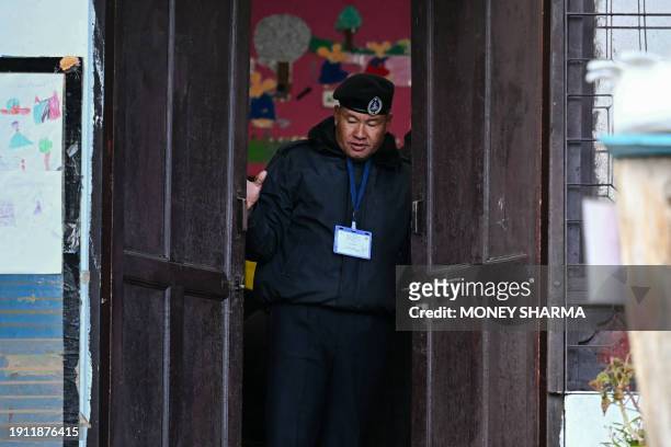 Security personnel closes the door of a polling station after the end of voting hours during general elections in Thimphu on January 9, 2024. The...