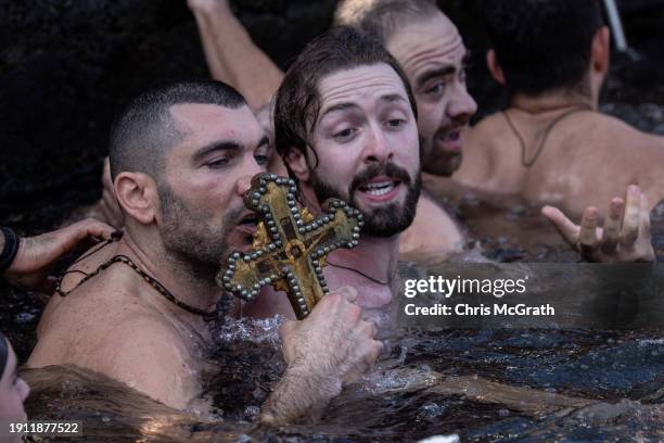 Swimmers kiss a wooden cross after taking part in the blessing of the water ceremony, as part of Epiphany day celebrations at the Church of Fener...