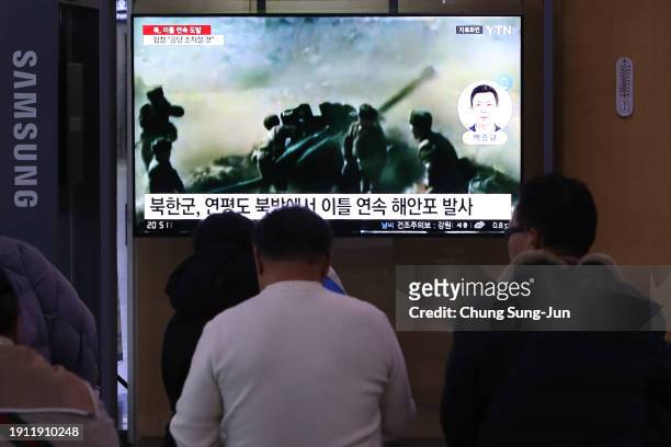 People watch a television screen showing a news broadcast with file footage of North Korea's artillery firing, at a railway station on January 06,...