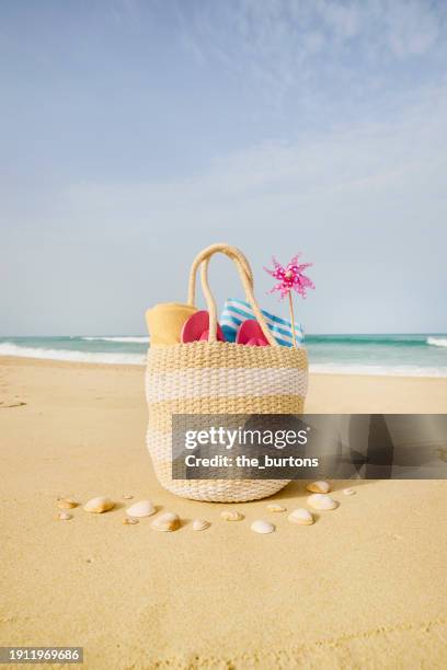 beach bag with pinwheel toy at beach and sea - tote bag stock pictures, royalty-free photos & images