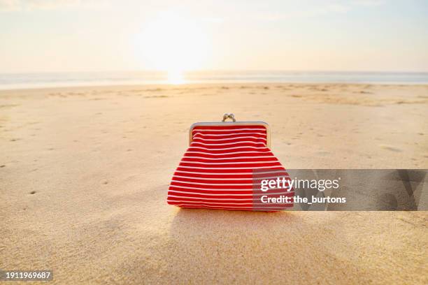 red change purse at beach during sunset - accessory foto e immagini stock