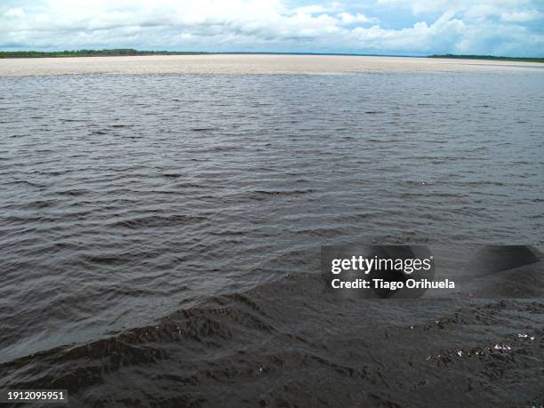 meeting of the waters of the negro river with the solimões river, forming the amazon river, near the city of manaus, brazil - solimões river stock pictures, royalty-free photos & images