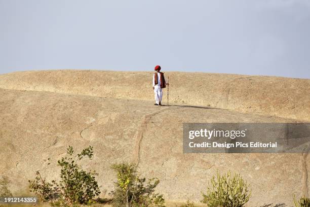 Nomadic Rabari Shepherd Wearing Coiled Turban And Traditional Dress In Desert Landscape.