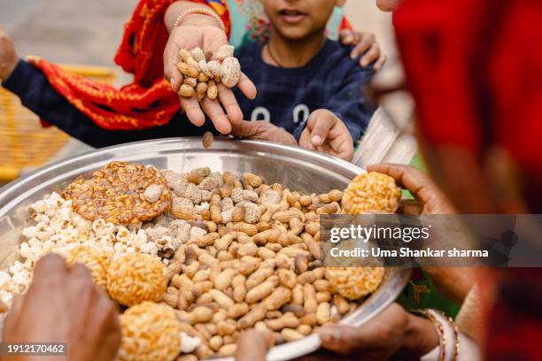 on the occasions of lohri and makar sankranti, peanuts, brittle-peanut chikki, and other eatables will be distributed. - people celebrate lohri festival stock pictures, royalty-free photos & images