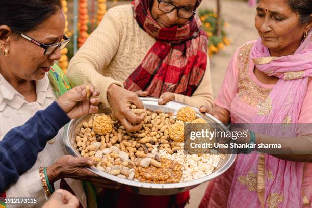 on the occasions of lohri and makar sankranti, peanuts, brittle-peanut chikki, and other eatables will be distributed. - people celebrate lohri festival stock pictures, royalty-free photos & images