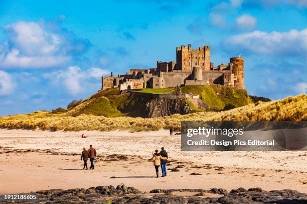 People on a beach near Lindisfarne Castle. Holy Island, Northumberland, England.