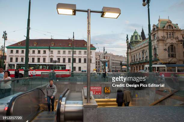 Pedestrians walk into a subway station as a bus and trolley ride through Prague's Republic Square. Republic Square, Prague, Czech Republic.