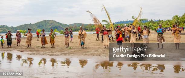 Village women in tapa bark cloth dresses preparing to perform traditional sing sing Melanesian tribal dance in Morobe Bay, Papua New Guinea. Morobe...