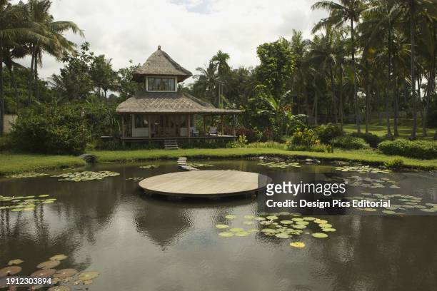 Small House With Thatched Roof And Pond With Deck. Denpasar, Bali, Indonesia.