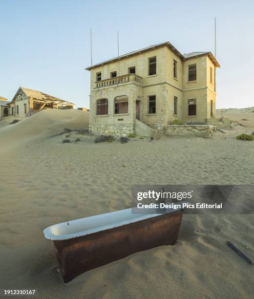 An Old Bathtub Lying In The Sand Outside Abandoned Houses. Kolmanskop, Namibia.
