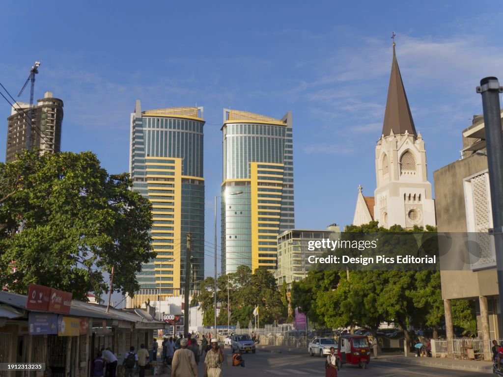 Pedestrians, St. Joseph's Cathedral, And Twin Buildings Against A Blue Sky; Dar Es Salaam, Tanzania