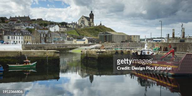 Boats In The Tranquil Harbour With Colourful Buildings On The Hillside And A Church On A Hilltop. Aberdeenshire, Scotland.