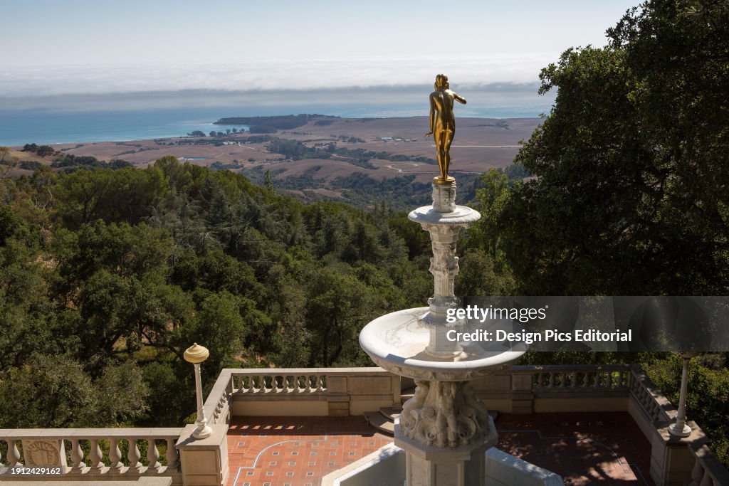 A gold statue and fountain on a veranda with a view of the Pacific and the San Simeon coast.; Hearst Castle, San Simeon, California