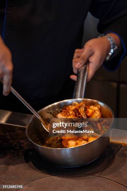 chef cuisinant un plat de curry de crevettes à la noix de coco du sri lanka dans une casserole en acier sur le comptoir de la cuisine - mode de cuisson des aliments photos et images de collection
