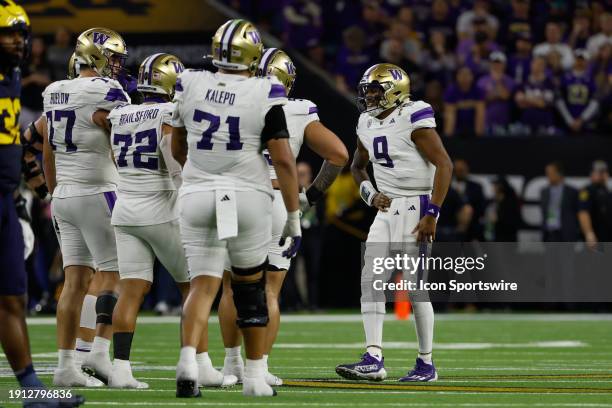 Washington Huskies quarterback Michael Penix Jr. Holds his side after getting hit hard on the previous play during the CFP National Championship game...