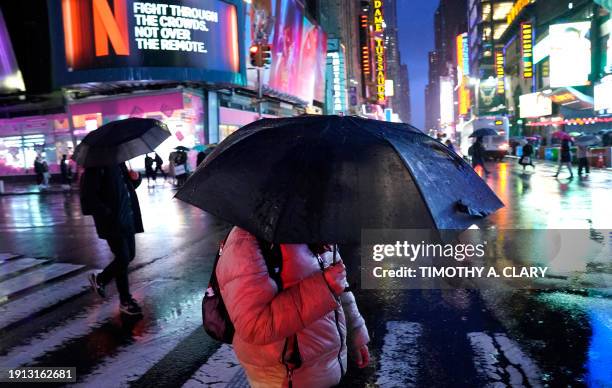 People hold their umbrellas as they walk through Times Square, New York, on January 9 as the city prepares for a winter storm that could bring...