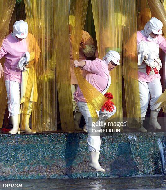 Women workers, dressed in protection clothes, go out from a purification workshop at Taiwan's Donghai Frozen Foods Company after work in the China's...