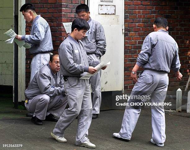 Employees of Daewoo Motors Co. Read union pamphlets outside of the Daewoo factory in Pupyong, some 40 Kms west of Seoul, 07 November 2000, as Daewoo...