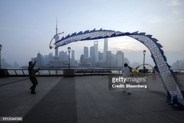 People fly kites on the Bund in front of buildings in Pudong's Lujiazui Financial District in Shanghai, China, on Tuesday, Jan. 9, 2024. China's...