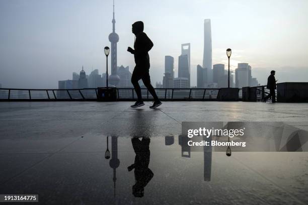 Jogger runs on the Bund in front of buildings in Pudong's Lujiazui Financial District in Shanghai, China, on Tuesday, Jan. 9, 2024. China's stock...