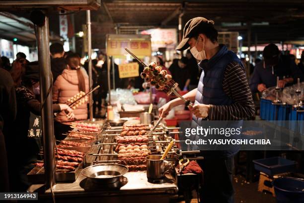 This photo taken on January 9, 2024 shows a man cooking at the Shanhua night market.