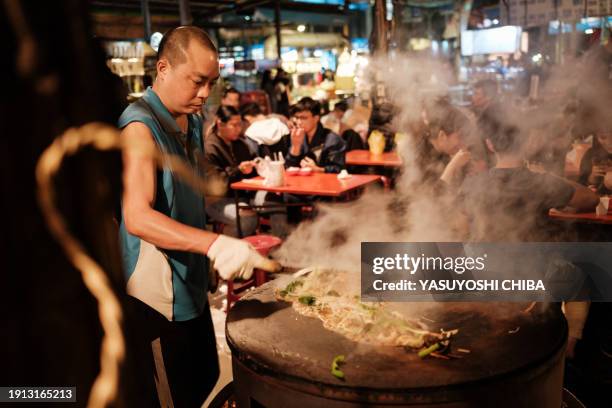 This photo taken on January 9, 2024 shows a man cooking on a steel plate at the Shanhua night market in Tainan.