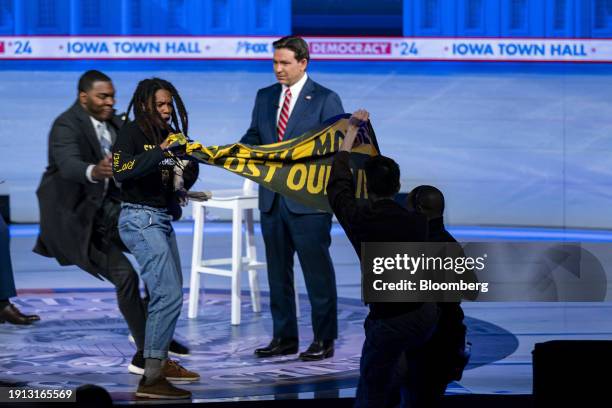 Demonstrators with a banner disrupt Ron DeSantis, governor of Florida and 2024 Republican presidential candidate, during a Fox News town hall on...