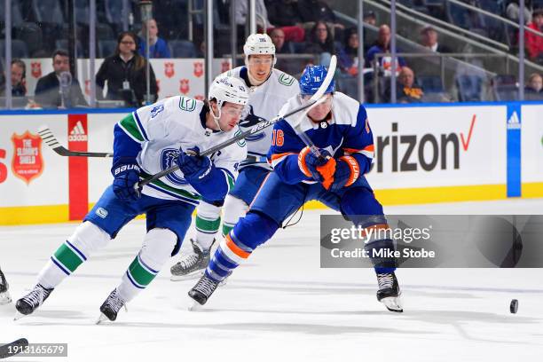 Quinn Hughes of the Vancouver Canucks and Julien Gauthier of the New York Islanders battle for the puck during the second period at UBS Arena on...