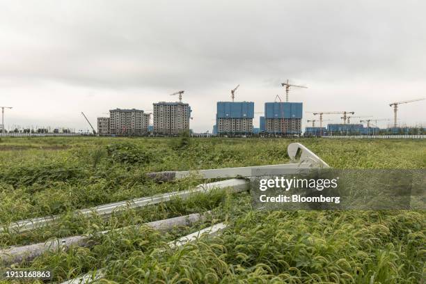 Light posts and road signs left in a field with the buildings under construction in the background, in Xiongan, China, on Monday, Aug. 21, 2023....