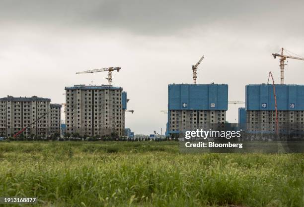 Light posts and road signs sit in a field while nearby buildings are under construction, in Xiongan, China, on Monday, Aug. 21, 2023. China has spent...