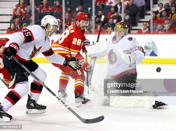 Goaltender Joonas Korpisalo and Jake Sanderson of the Ottawa Senators battle against Elias Lindholm of the Calgary Flames in the third period at the...