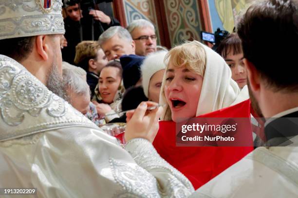 Priest is sharing the Holy Communion with the congregation during the divine liturgy at St. Michael's Golden-Domed Cathedral on Epiphany in Kyiv,...