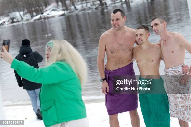 Men are posing for a photo after bathing in the Dnipro River in Hidropark on Epiphany in Kyiv, Ukraine, on January 6, 2024.