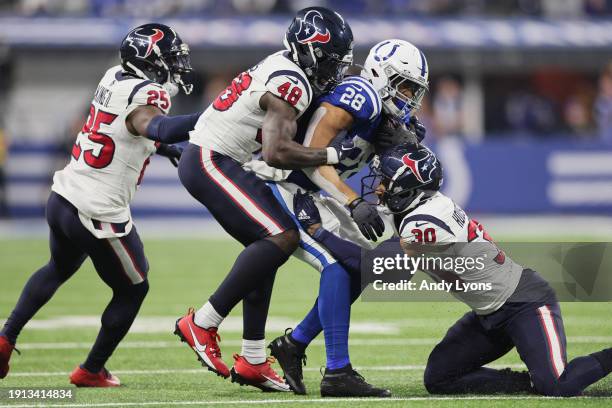 Jonathan Taylor of the Indianapolis Colts is tackled by DeAndre Houston-Carson and Christian Harris of the Houston Texans during the first quarter at...