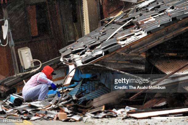 Man takes out personal belongings from a collapsed house on January 7, 2024 in Wajima, Ishikawa, Japan. A tsunami warning was issued Japan's...