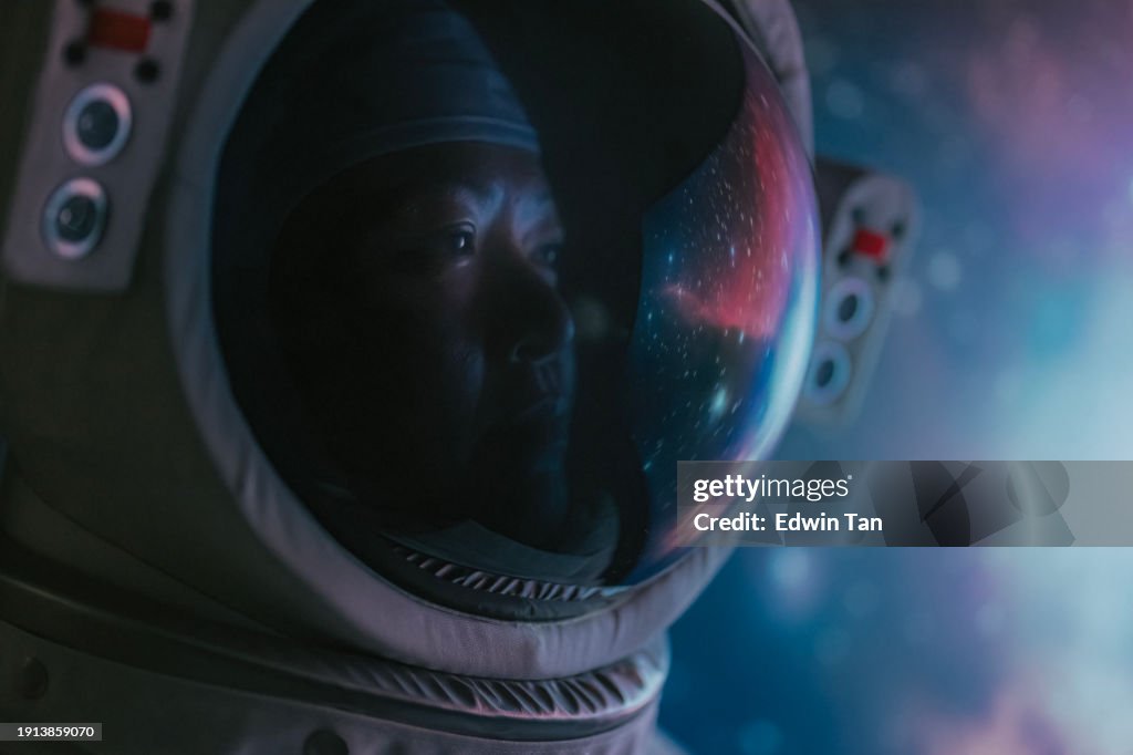 Asian chinese mid adult female astronaut looking at earth through window from spaceship at outer space
