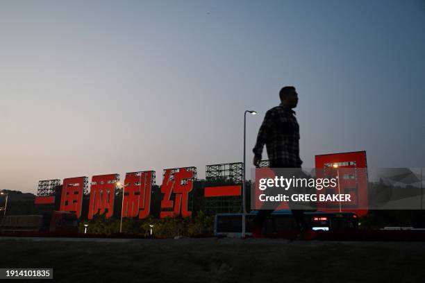 Man walks near a giant propaganda slogan which reads "One Country, Two Systems, Unify China", which can be seen from Taiwan's Kinmen Island, on a...