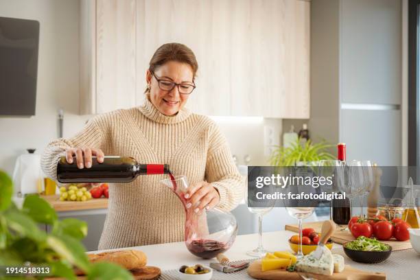 woman pouring red wine from bottle into decanter - day in the life series stock pictures, royalty-free photos & images