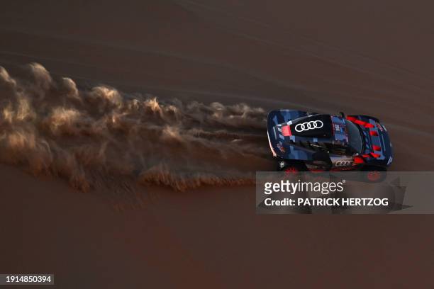 Team Audi Sport's Spanish driver Carlos Sainz and his Spanish co-driver Lucas Cruz steer their car in the dunes as they compete in Stage 5 of the...