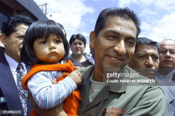 Ex-coup leader Lucio Gutiérrez carries a child while walking through Quito 21 October 2002. Gutiérrez and banana magnate Alvaro Noboa appeared to be...