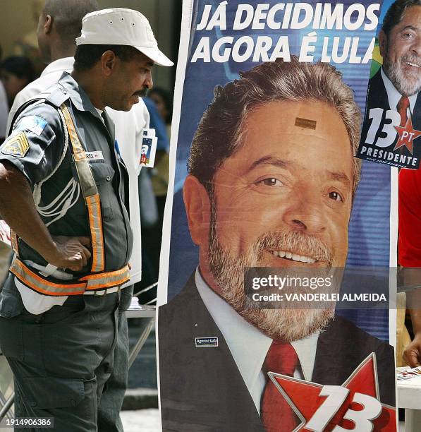 Police agent observe an election poster of presidential candidate of Brazil, Luis Inacio Lula da Silva, of the worker's party, in a street of Rio de...