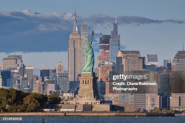 view of the statue of liberty and the empire state building in the late afternoon - new york harbour stock pictures, royalty-free photos & images