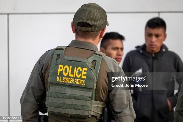 Border Patrol agent watches as immigrants prepare to board a bus after crossing the U.S.-Mexico border on January 07, 2024 in Eagle Pass, Texas....