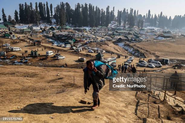 Vendors are carrying items as they walk towards a temple on a sunny day at the ski resort in Gulmarg, Baramulla, Jammu and Kashmir, India, on January...