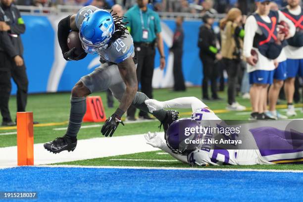 Jahmyr Gibbs of the Detroit Lions scores a touchdown while defended by Camryn Bynum of the Minnesota Vikings during the first quarter at Ford Field...