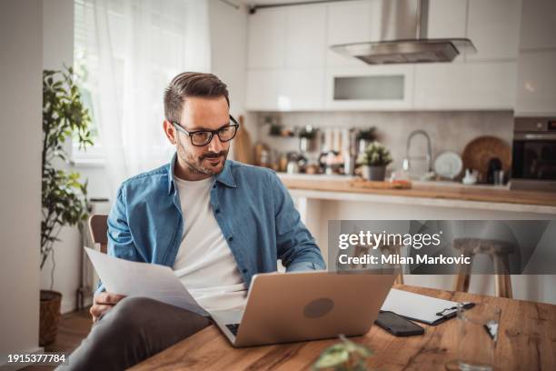 a young man works from home using a laptop - portrait of pensive young businessman wearing glasses stock pictures, royalty-free photos & images